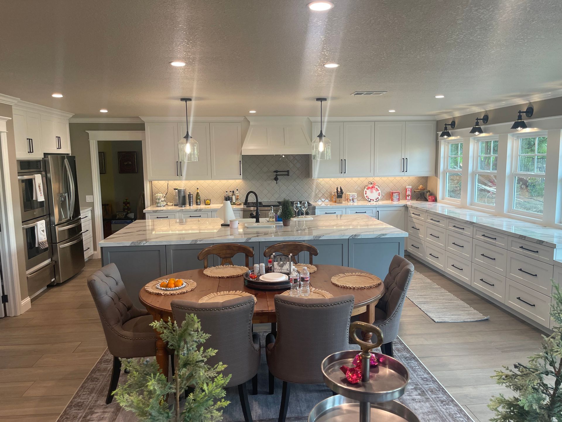 A modern kitchen with a round dining table, a large island, and white and gray cabinets.