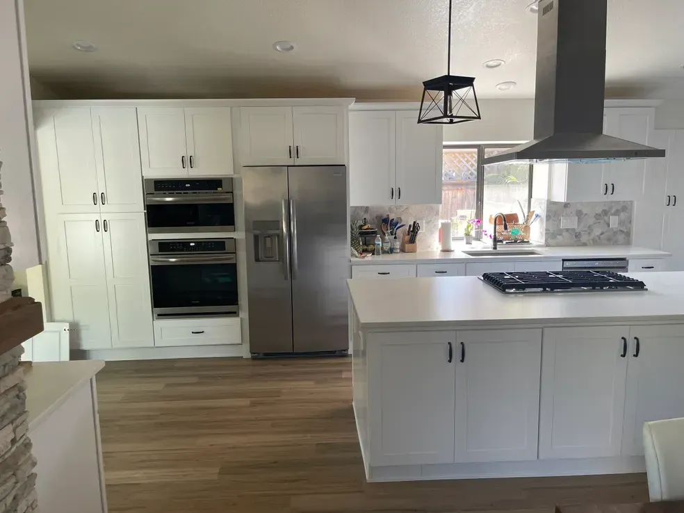 White kitchen with stainless steel appliances, island, and cabinets.