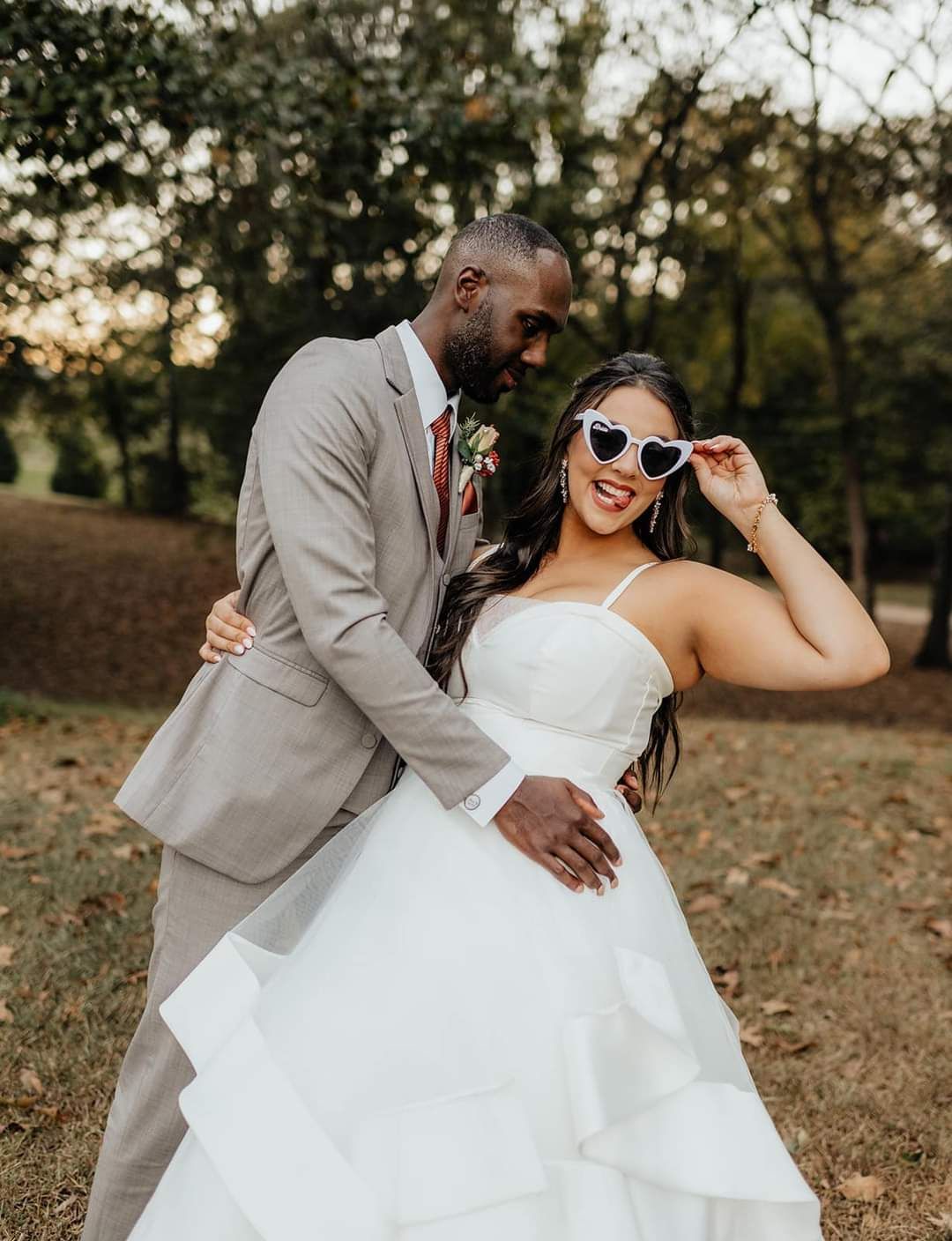 bride wearing heart sunglasses embraced by groom