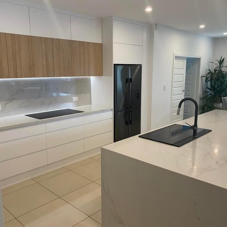 A Kitchen With White Cabinets and a Black Refrigerator — Kenross Kitchens In Terrigal, NSW