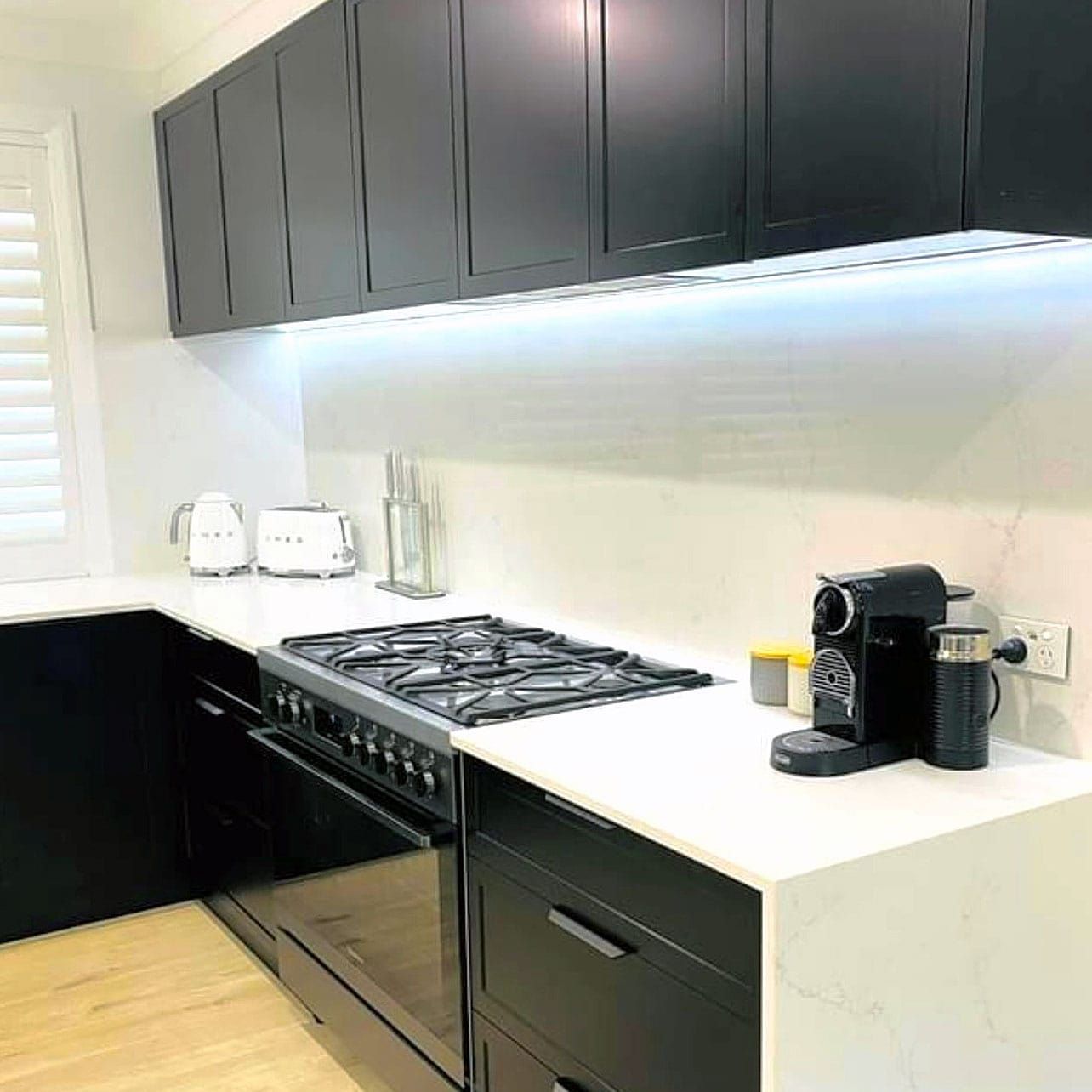 A Kitchen With Black Cabinets and a Stove Top Oven — Kenross Kitchens In Erina, NSW