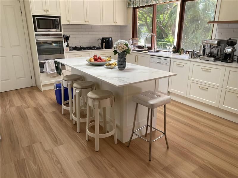 A Kitchen With a Large Island in the Middle and Stools  — Kenross Kitchens In Avoca Beach, NSW