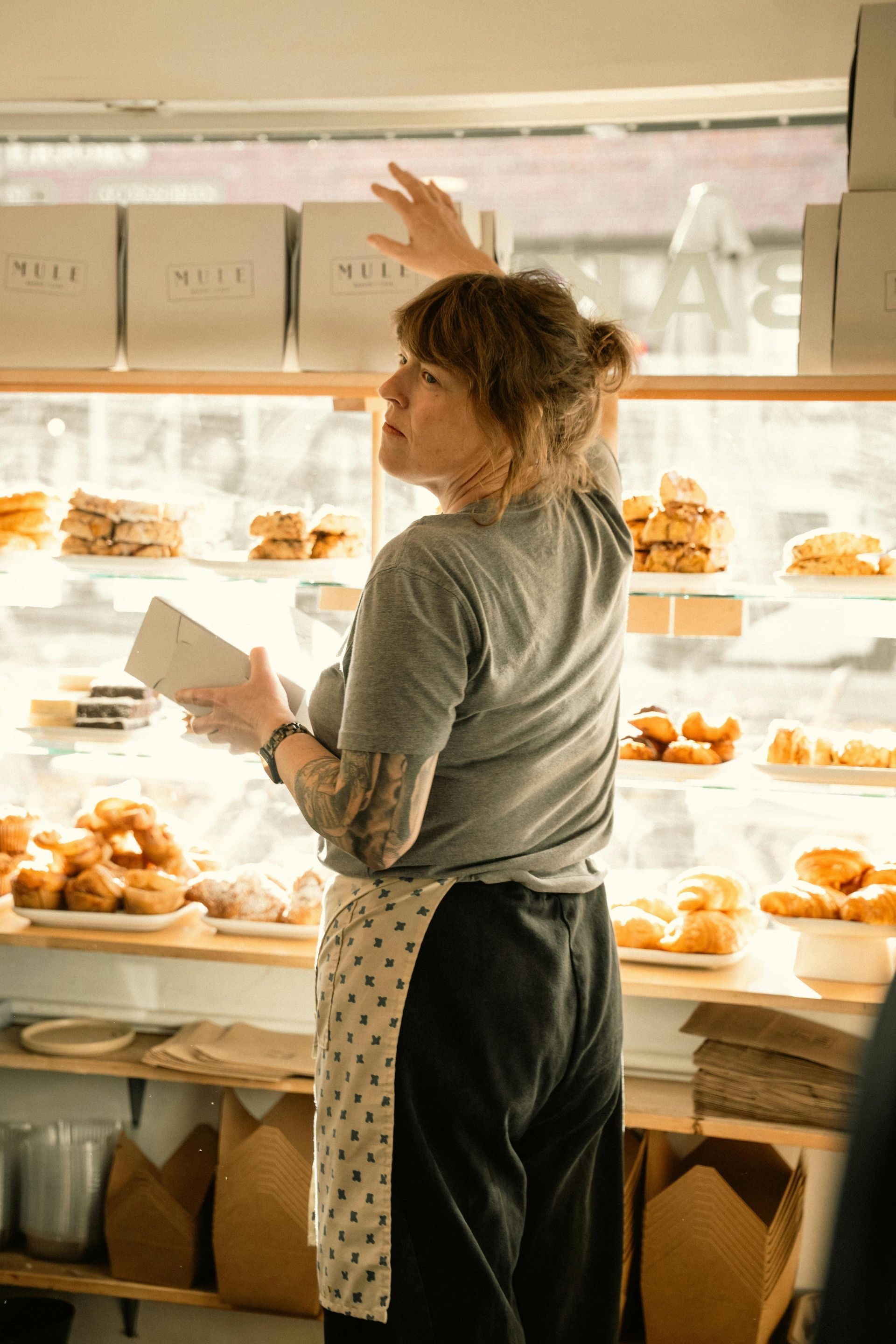 Hand with gold wedding ring on a wooden surface, blurred outdoor background.