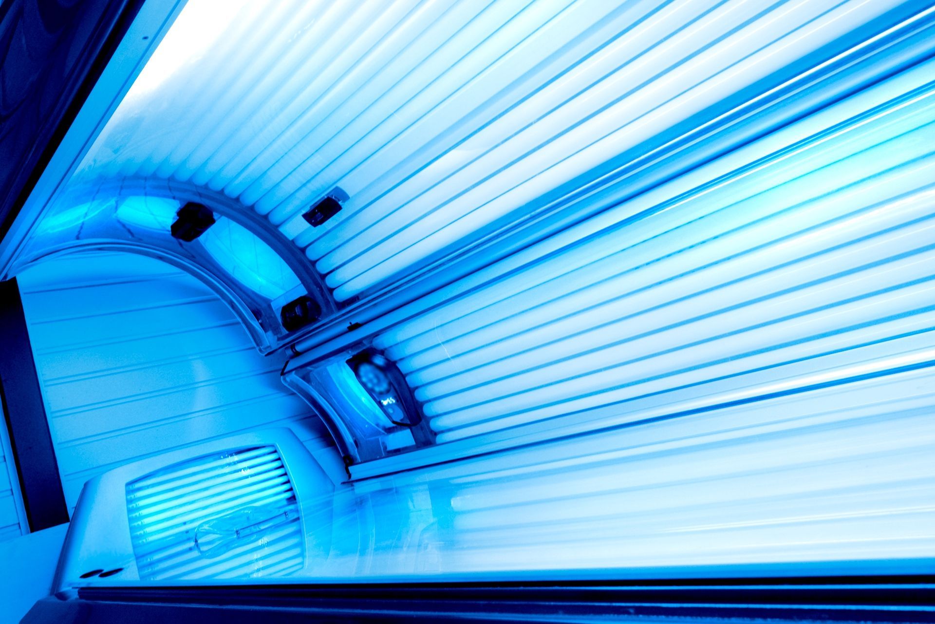 Interior of a tanning bed, lit with bright blue fluorescent lights.