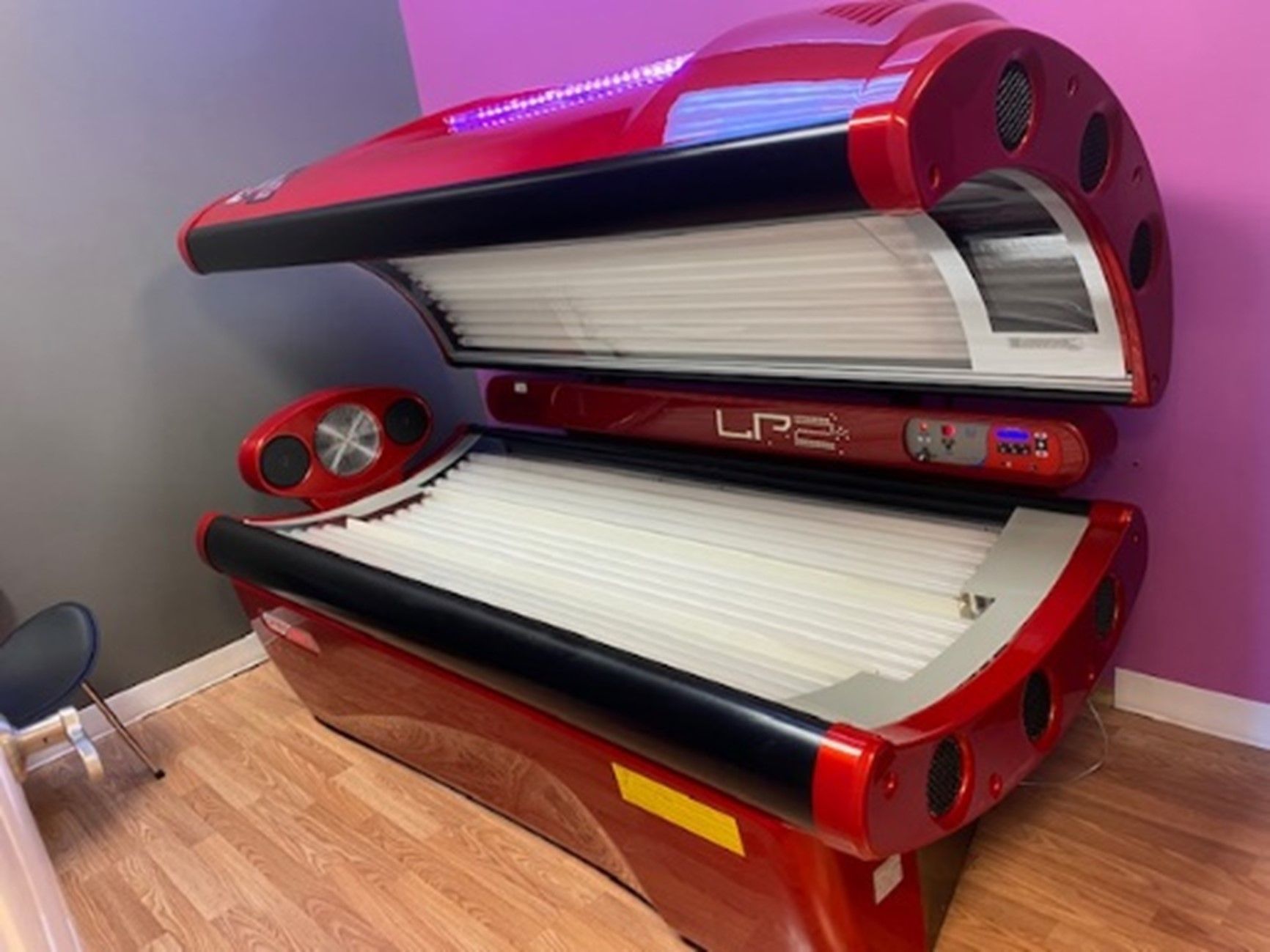 Red tanning bed in a salon setting, featuring white lamps, a digital display, and a black rim.