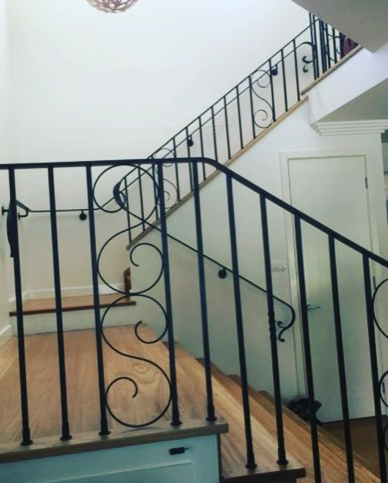 A Staircase With a Wrought Iron Railing and Wooden Steps — Barry Smith Engineering Pty Ltd in Coffs Harbour, NSW