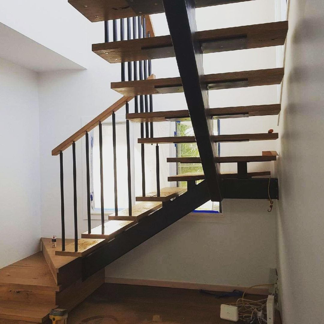A Wooden Staircase With a Metal Railing in a Room — Barry Smith Engineering Pty Ltd in Coffs Harbour, NSW