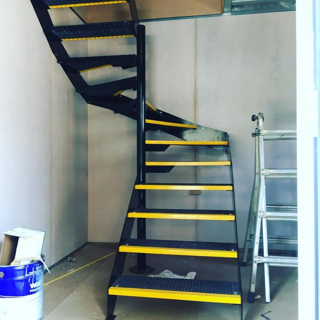 A Spiral Staircase With Yellow Steps in a Room — Barry Smith Engineering Pty Ltd in Coffs Harbour, NSW