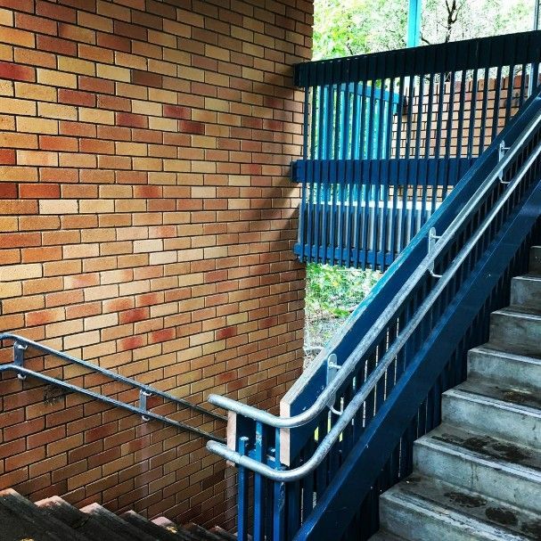 A Staircase With a Blue Railing and a Brick Wall — Barry Smith Engineering Pty Ltd in Coffs Harbour, NSW