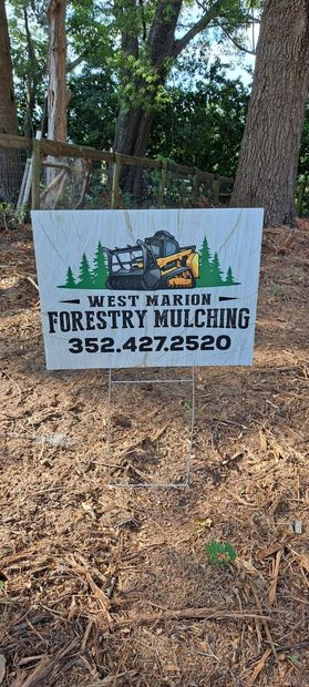 A sign for forestry mulching is sitting on top of a pile of mulch.