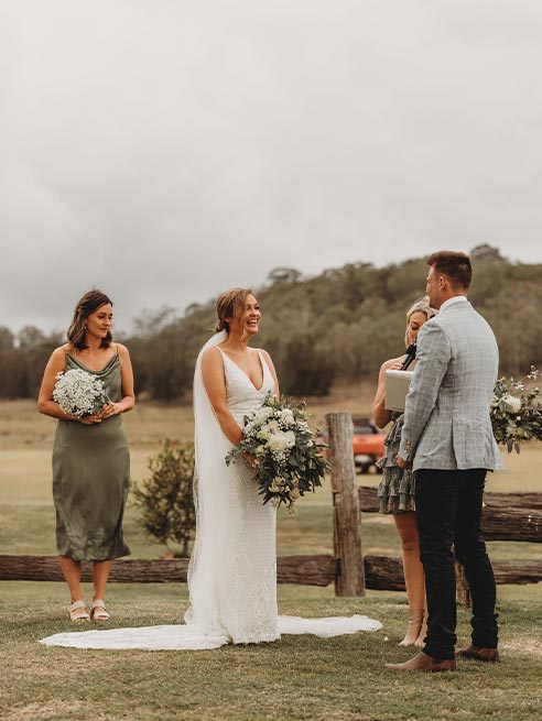 A bride and groom are standing in a field during their wedding ceremony.
