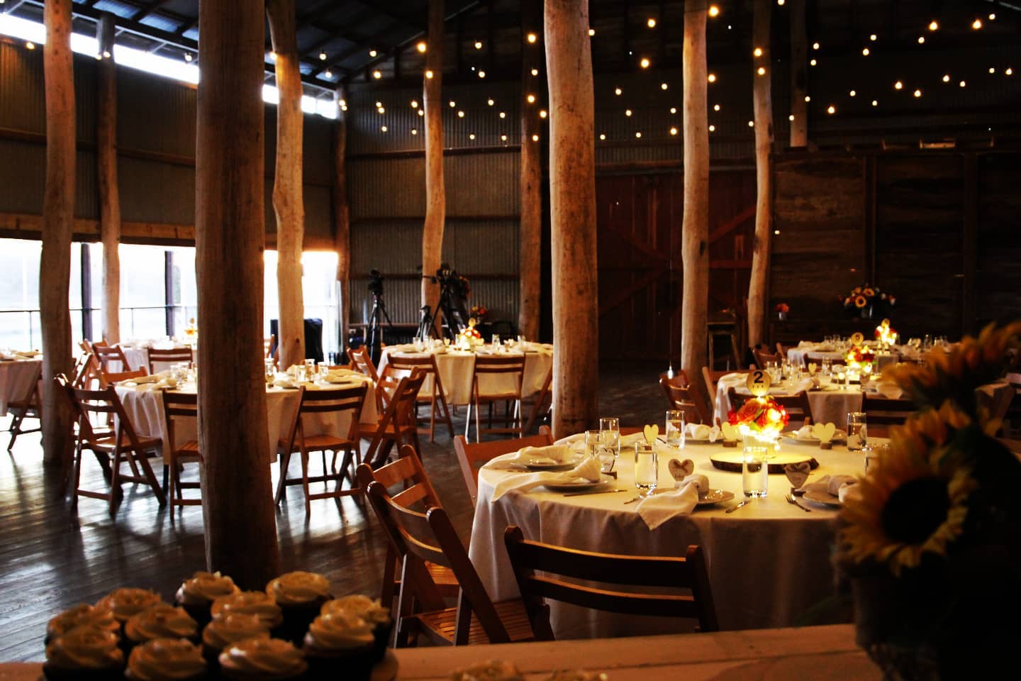 A large room with tables and chairs set up for a wedding reception