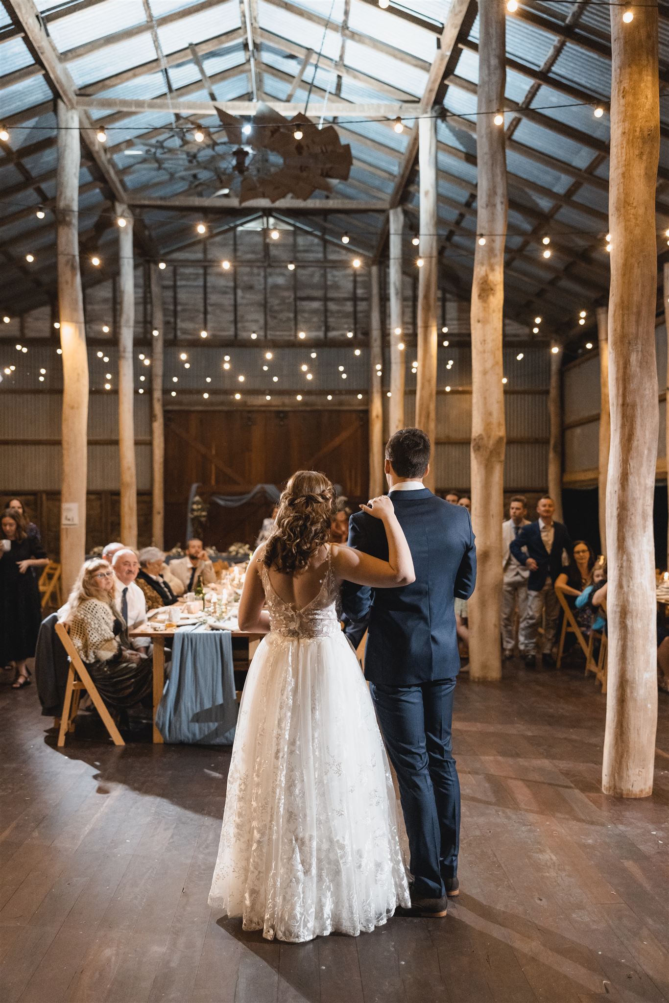 A bride and groom are dancing in a large room at their wedding reception.
