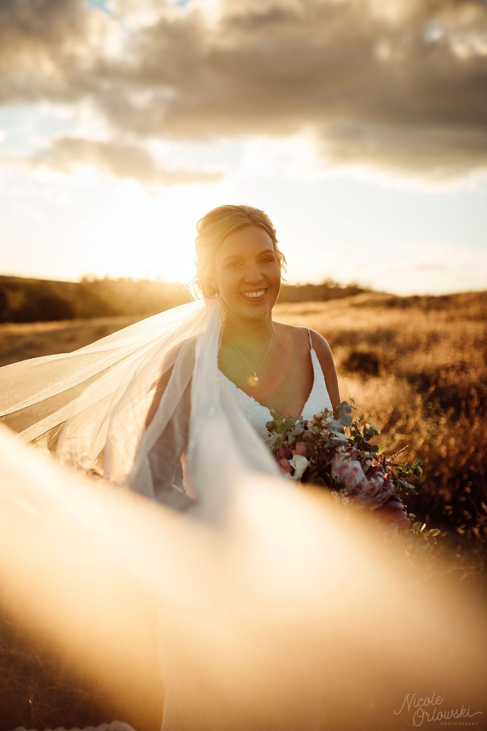 The bride is wearing a veil and holding a bouquet of flowers.