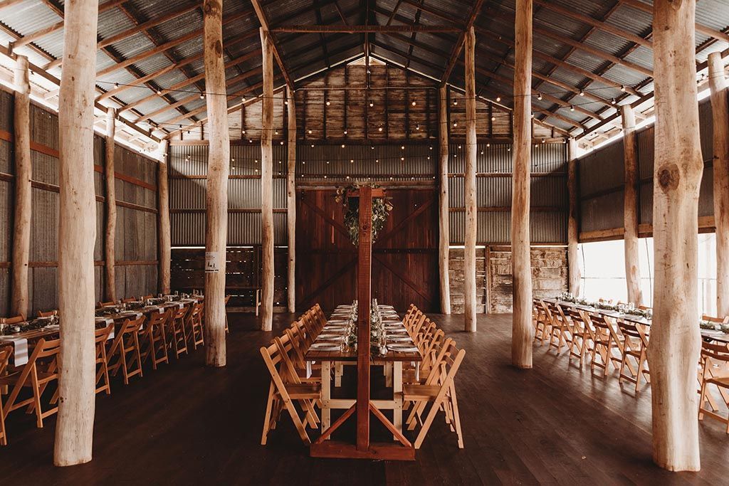 A large wooden barn filled with tables and chairs.