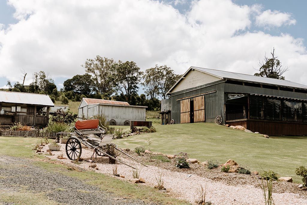 A horse drawn carriage is parked in front of a barn.