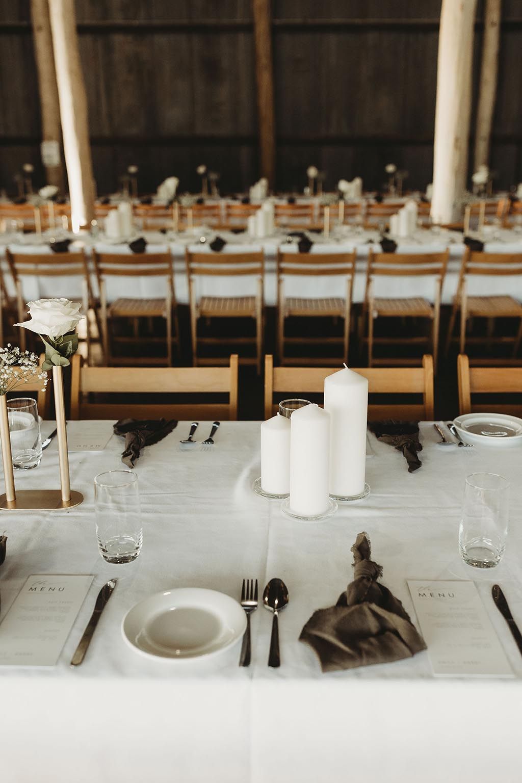 A long table set for a wedding reception with plates , candles , and silverware.