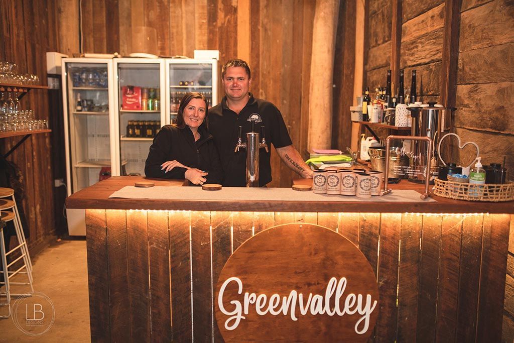 A man and a woman are standing behind a wooden bar.