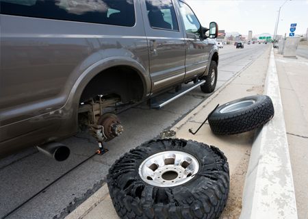 Brown SUV with a flat tire on the side of a highway. Spare tire and jack visible.