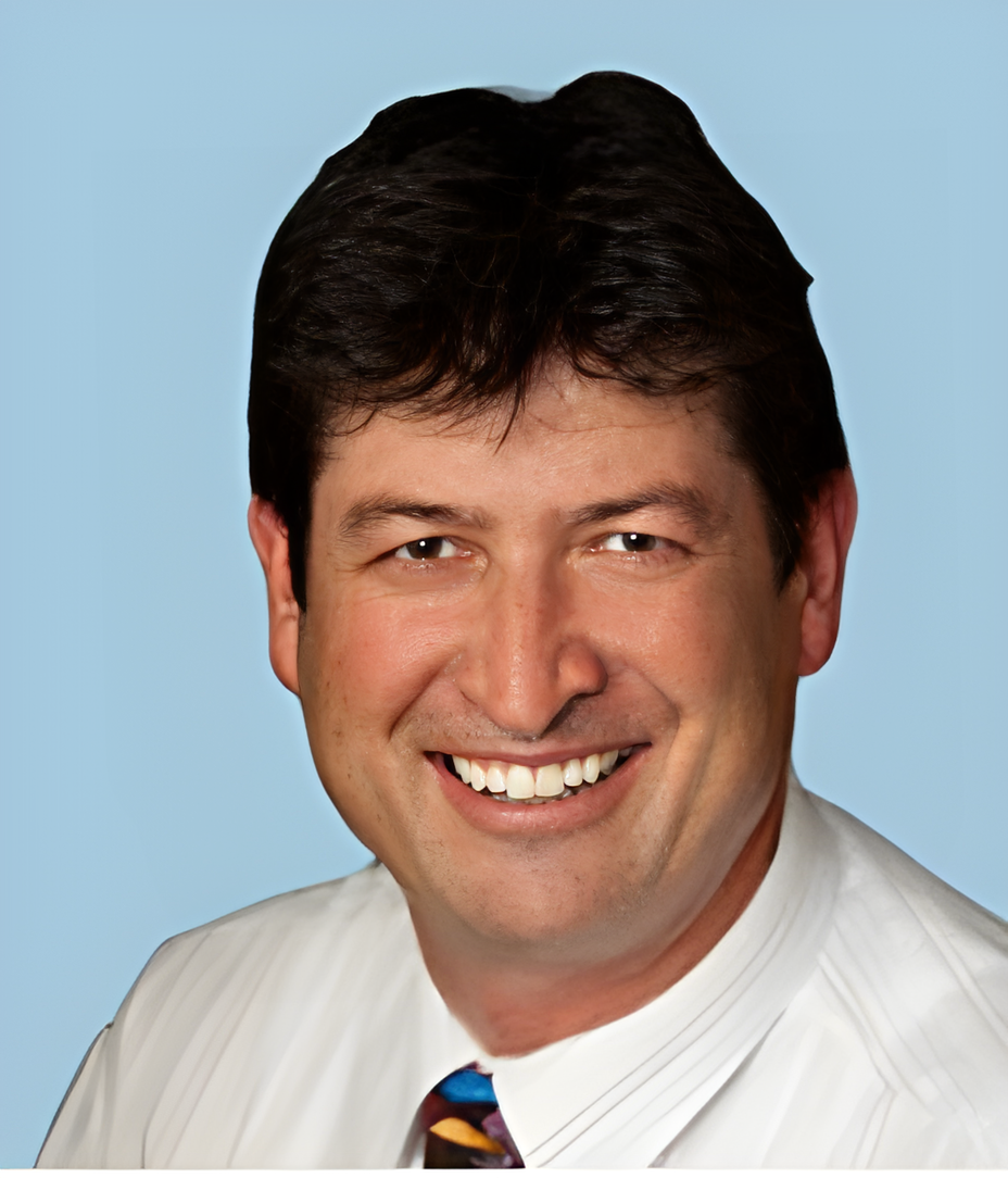 A man in a white shirt and tie smiles for the camera