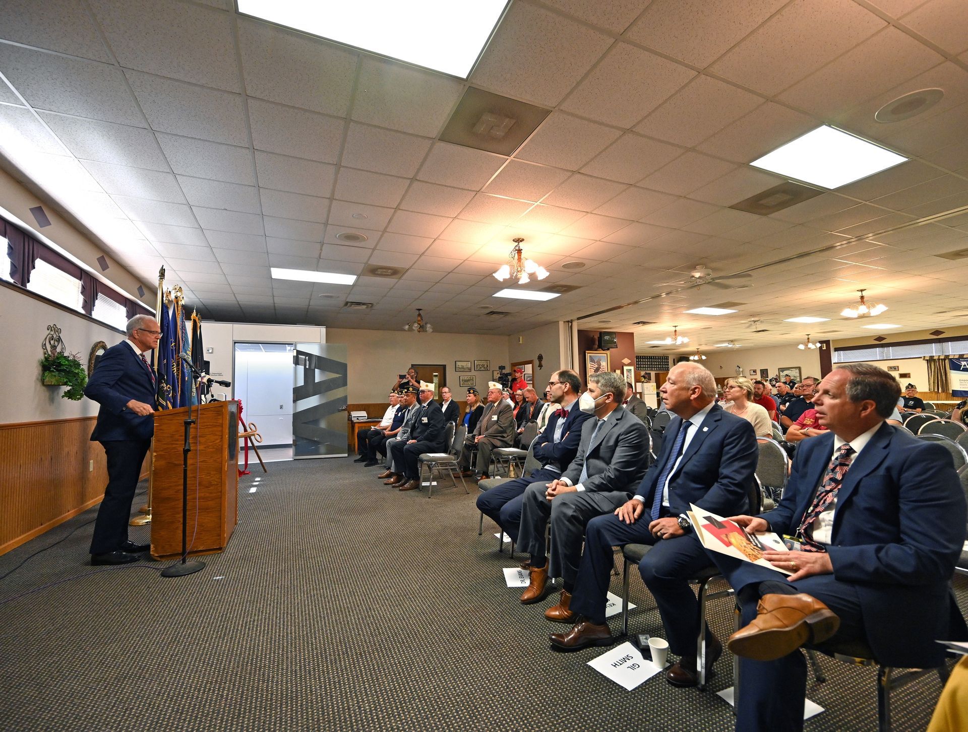 A man is giving a speech to a group of people sitting in chairs.