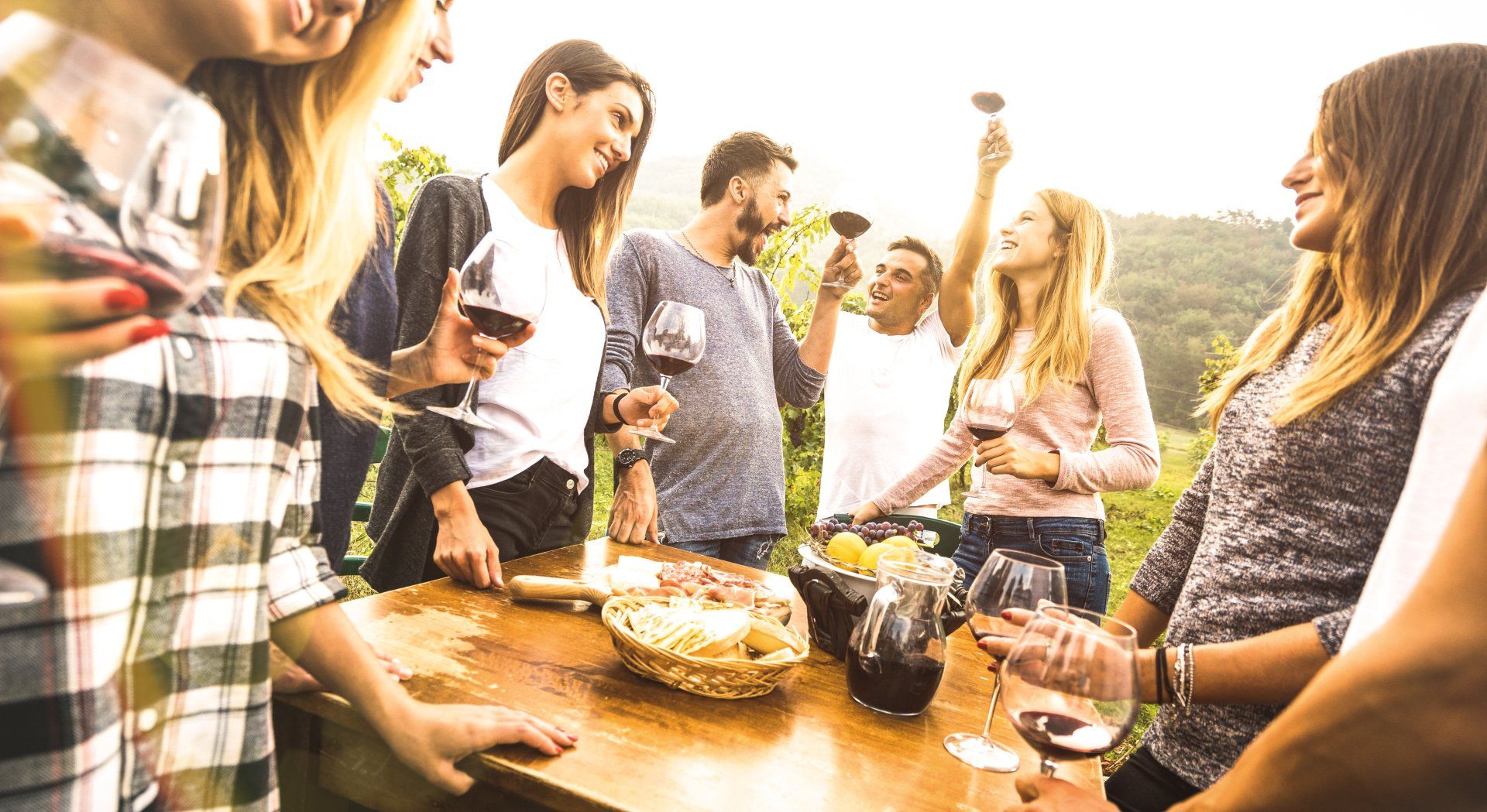 A group of people are standing around a table drinking wine.