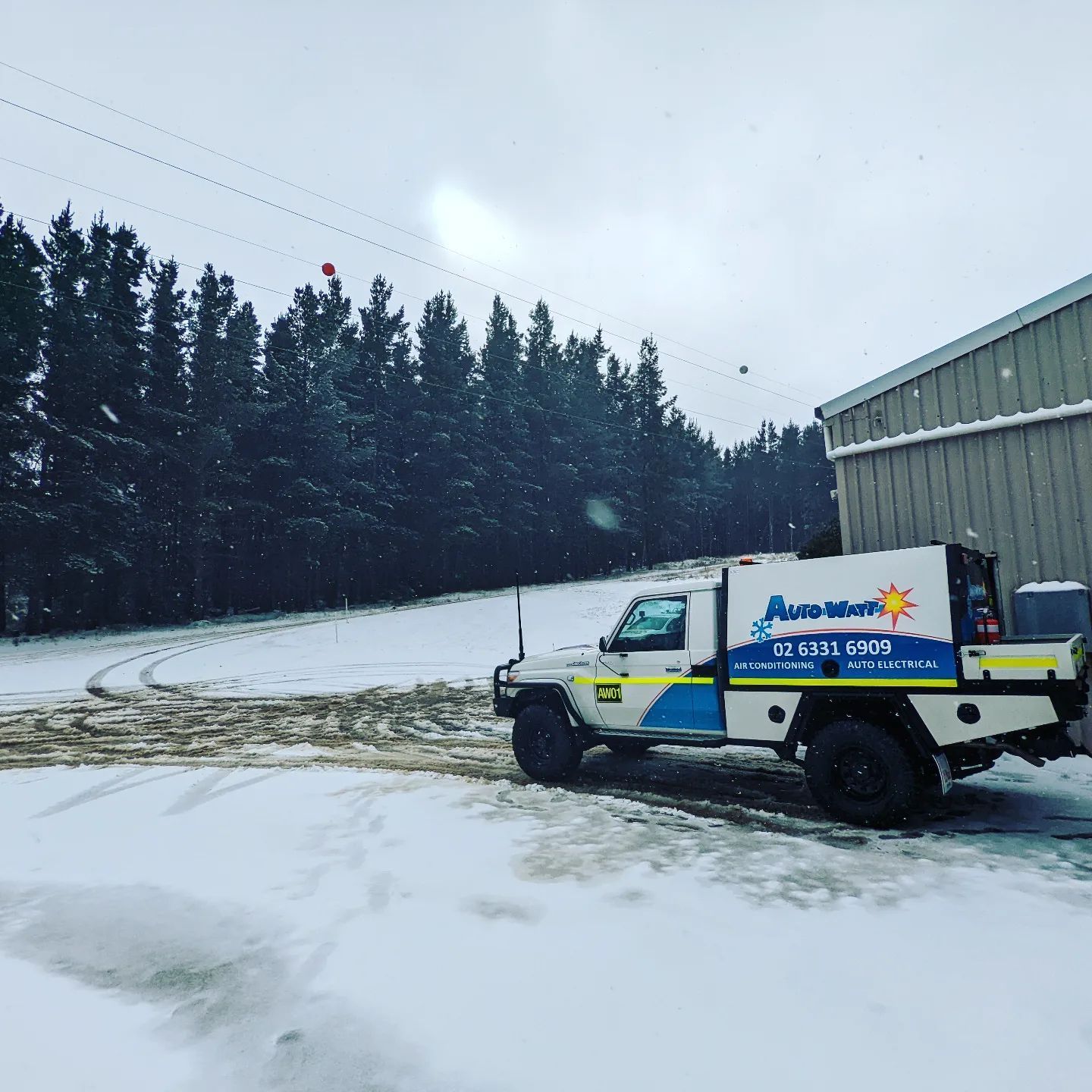 Utility truck in snow near a building and forest — Auto Watt in Kelso, NSW