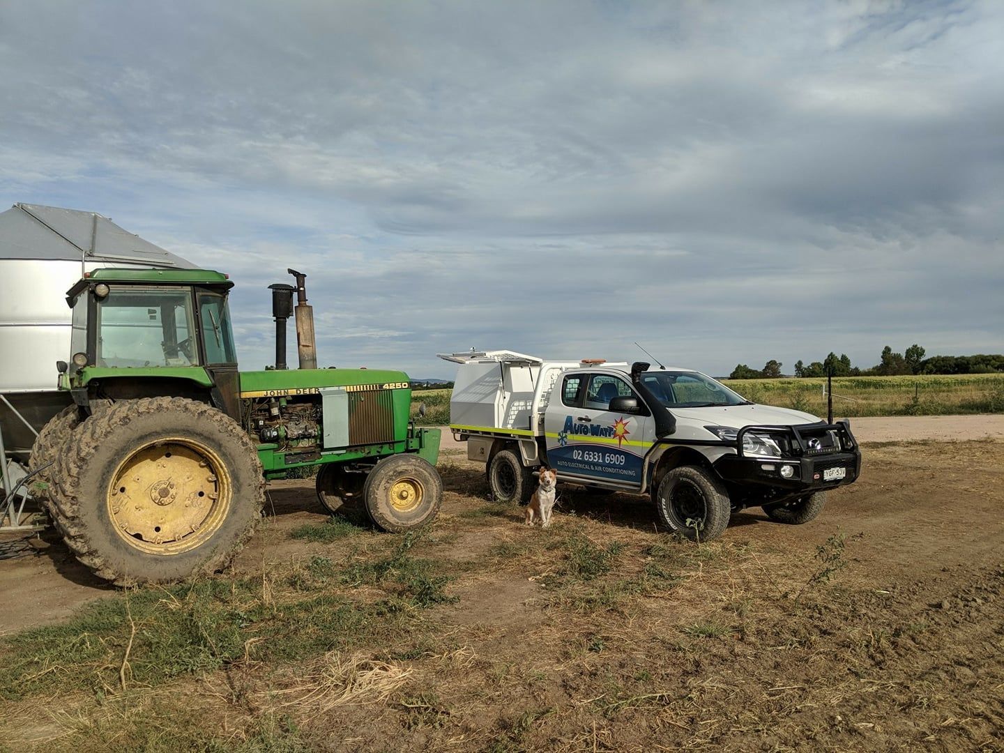Green Tractor Next to a White Truck With a Camper in a Field — Auto Watt in Kelso, NSW