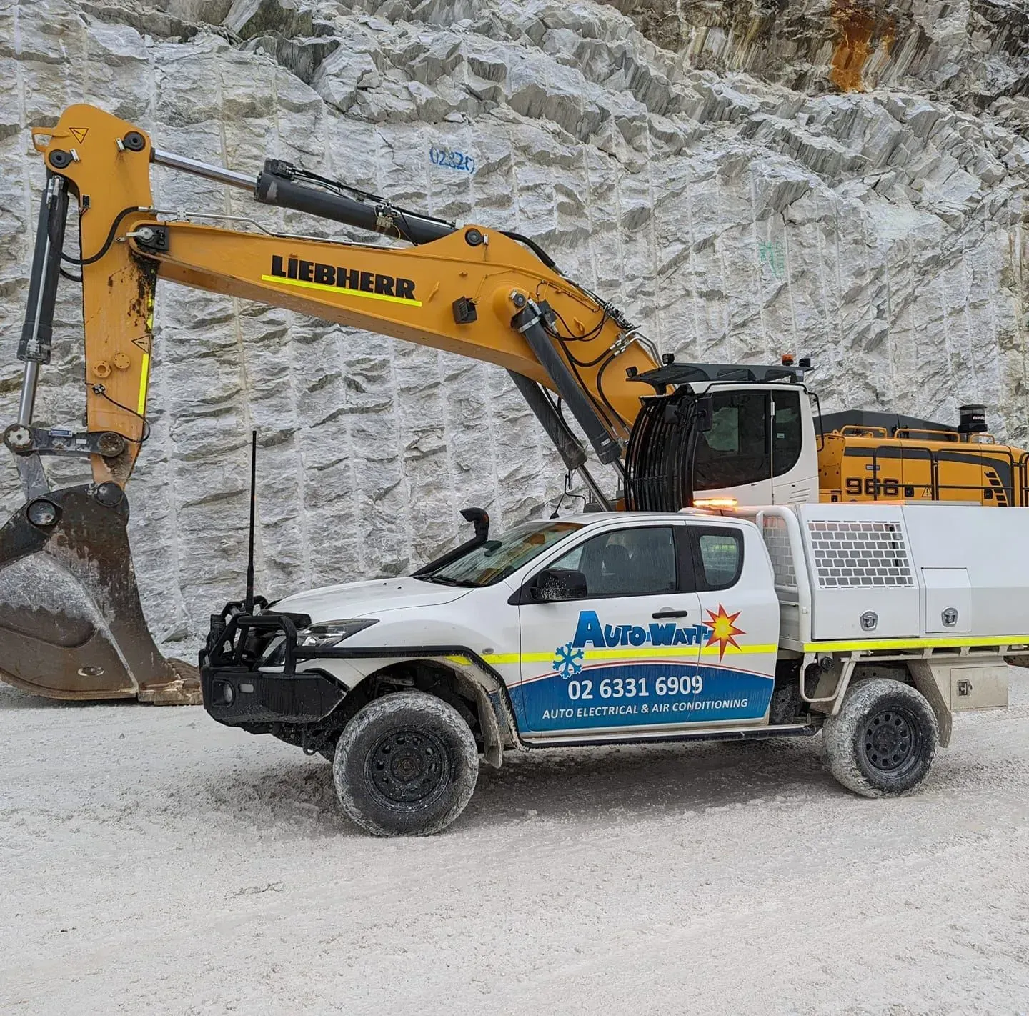 White truck with work lights and yellow excavator in front of a rock face — Auto Watt in Kelso, NSW