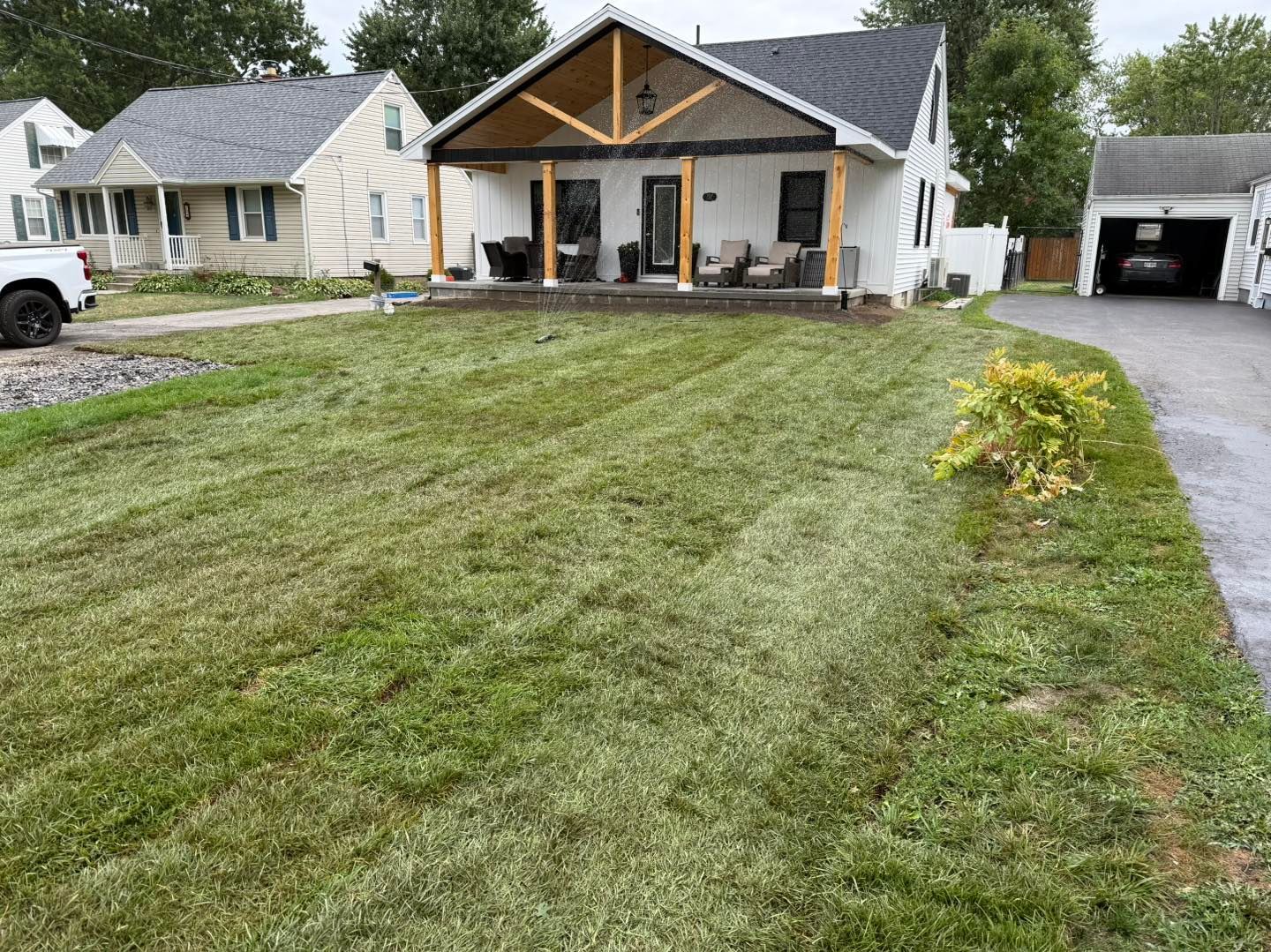 White house with porch; Sod Install lawn in front.