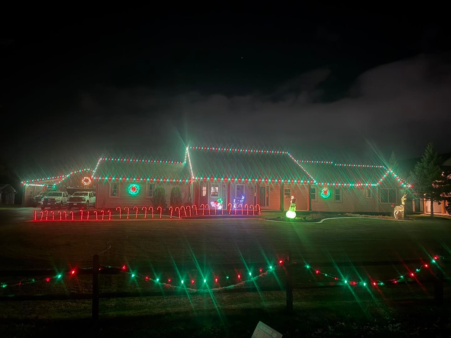 House decorated with red and green Christmas lights at night.