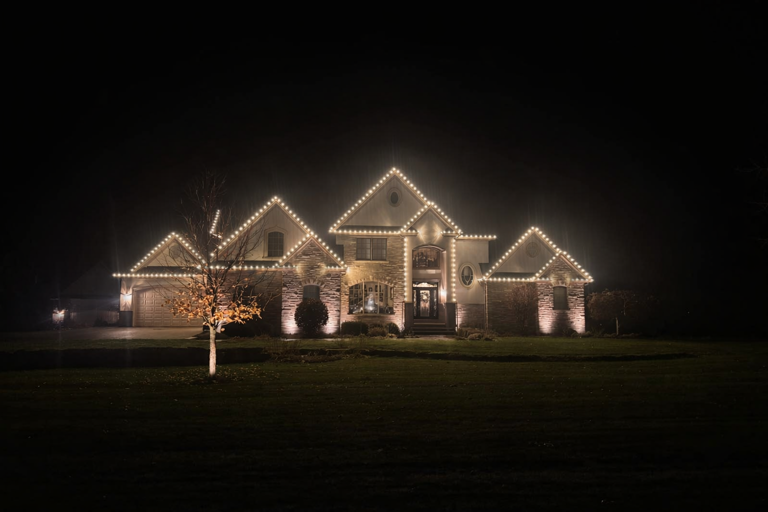 A house at night, decorated with white Christmas lights on the roof and facade.