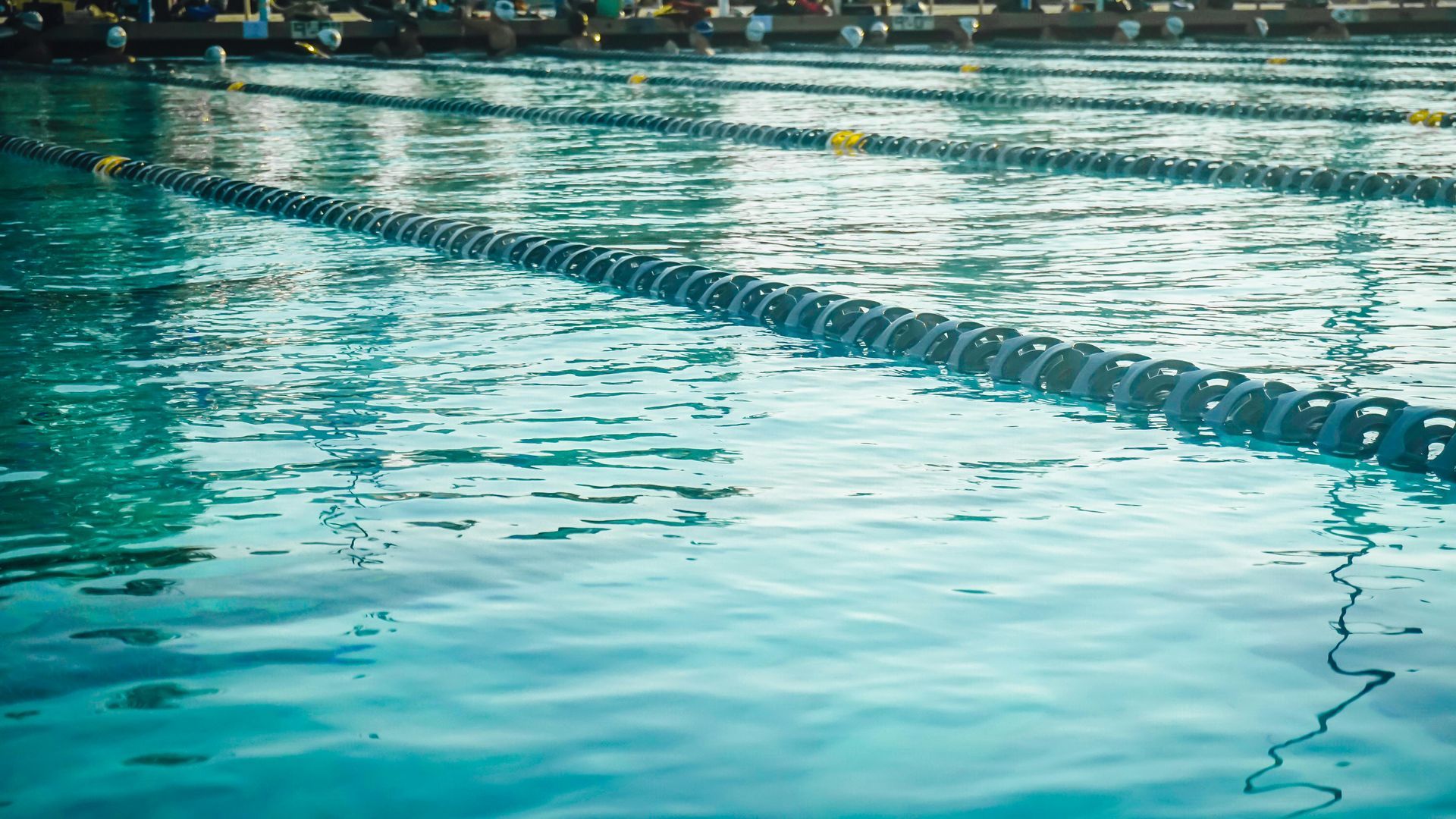 Empty outdoor swimming pool with turquoise water and lane ropes