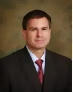 A man in a suit and tie is smiling for the camera