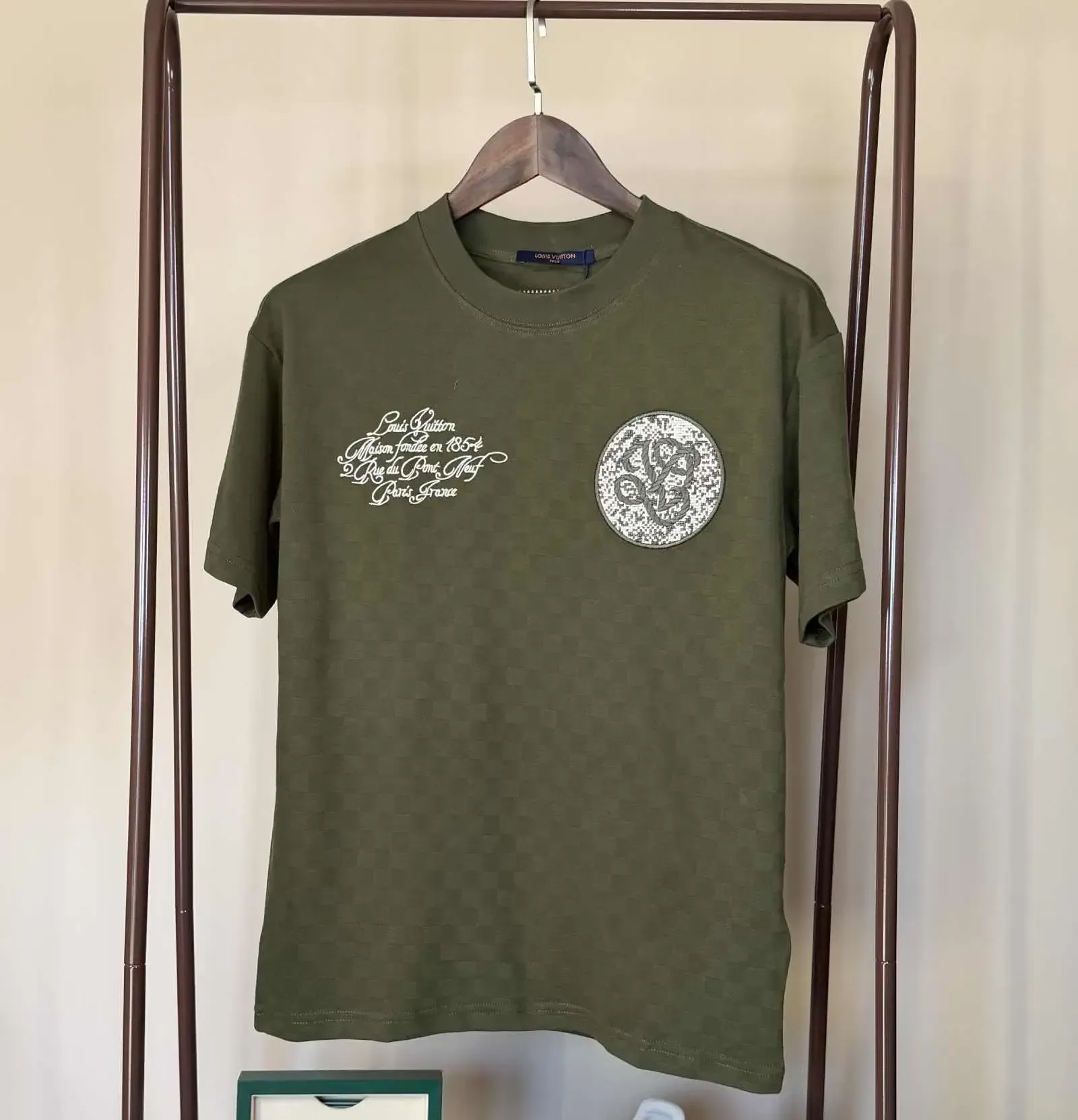 Green t-shirt with white designs on a clothes rack.