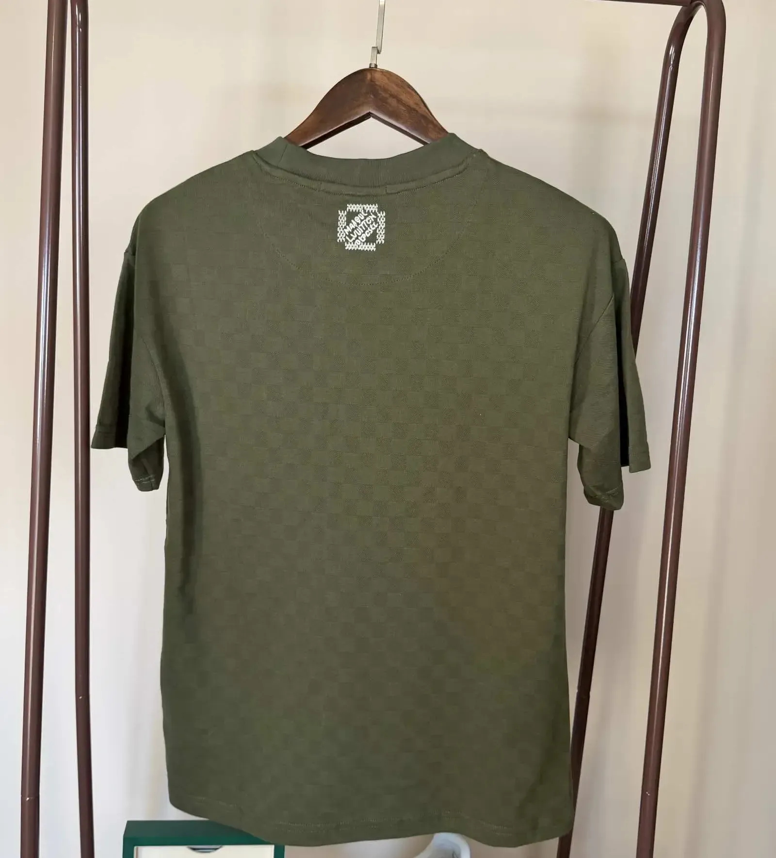Green t-shirt with white designs on a clothes rack.