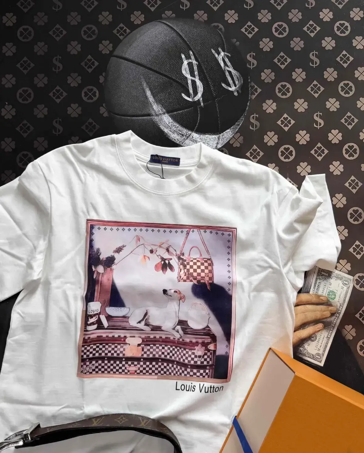 White LVE t-shirt with a printed design, a basketball, and a designer box on a logo-patterned surface.