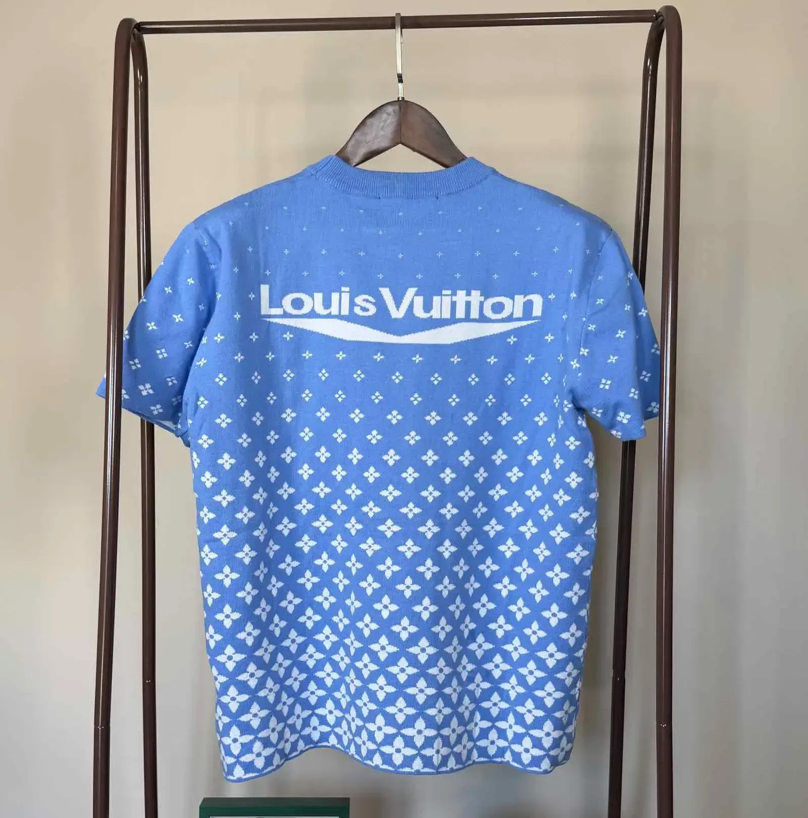 Blue patterned short-sleeve shirt with a small chest logo, hanging on a clothing rack.