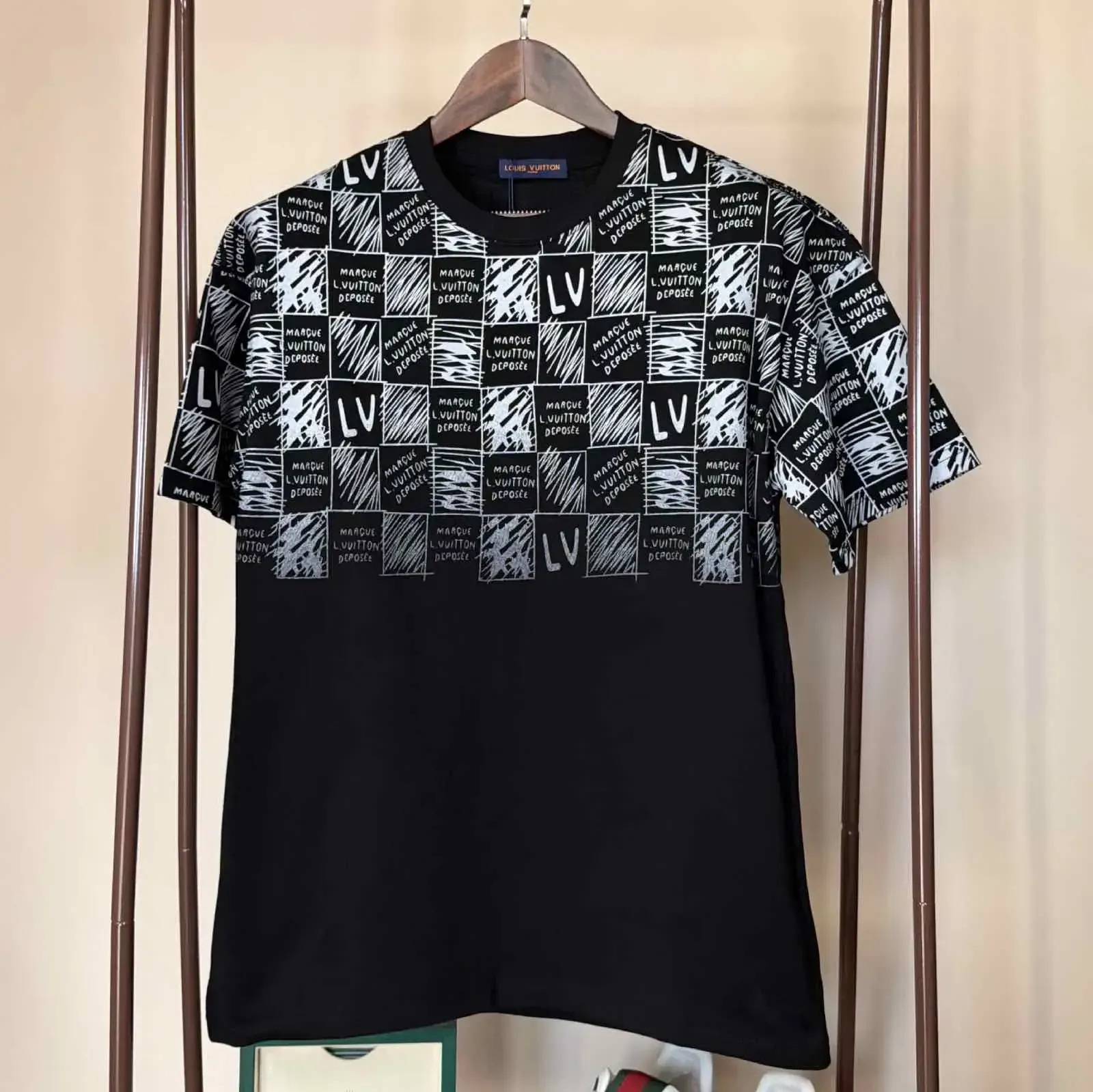 Black and white LVE t-shirt with checkered print on top half, hanging on a rack.