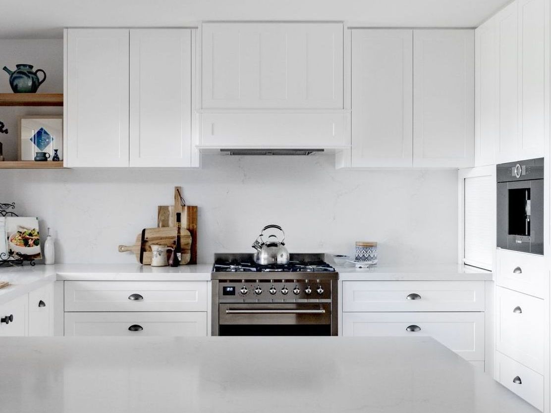 A white shaker profile kitchen with white cabinets and a freestanding stainless steel cooktop and oven.