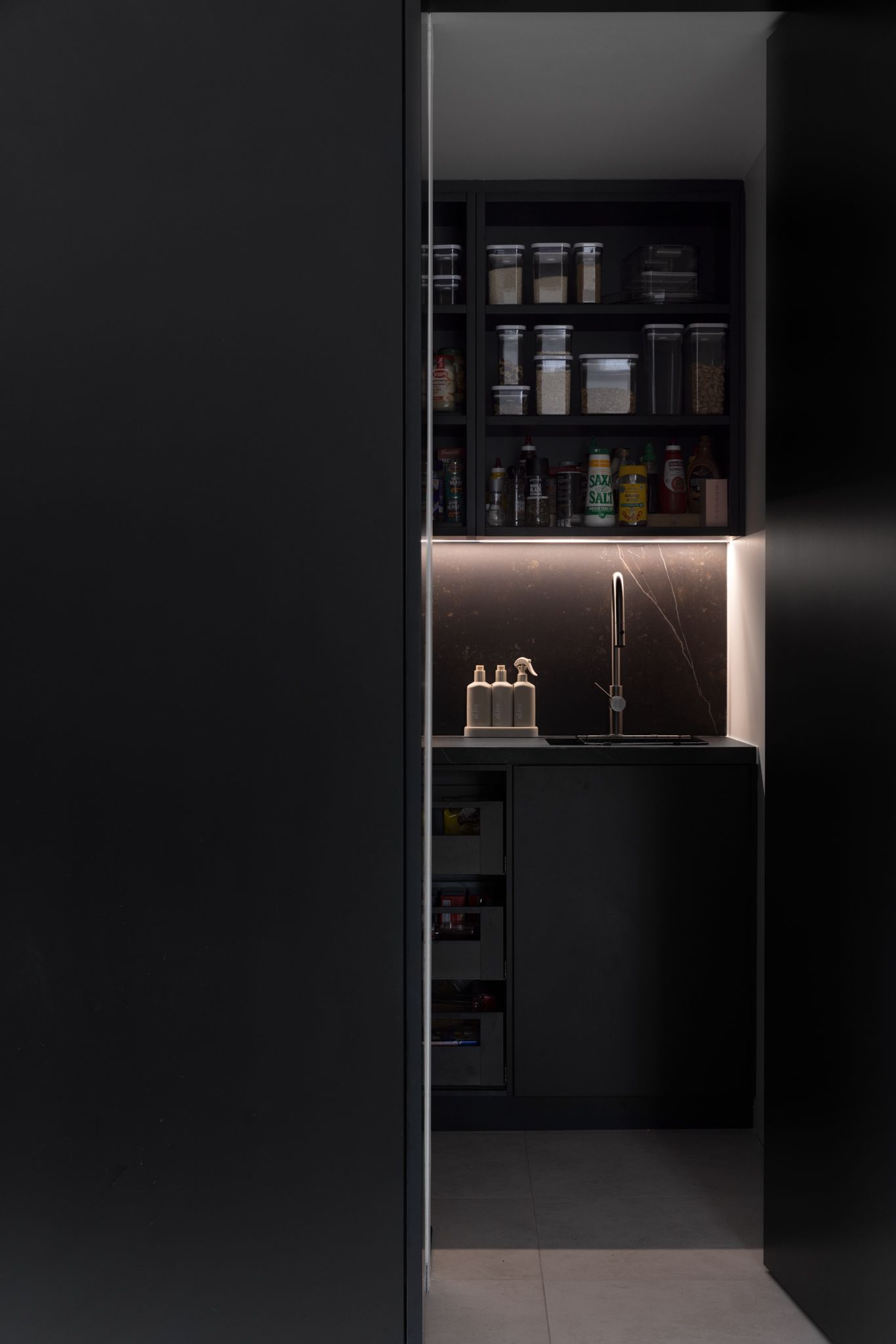 A contemporary all-black kitchen with matte joinery and black veined stone, exuding a sleek and modern aesthetic.