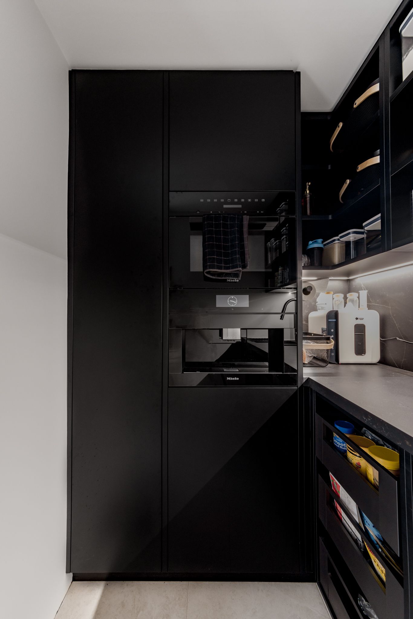 A Vista Kitchens Newcastle locally manufactured modern Butler's Pantry in black with open shelves and drawers. LED strip lighting is recessed into the joinery, adding a stylish touch.