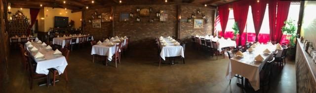 A large dining room filled with tables and chairs and red curtains.