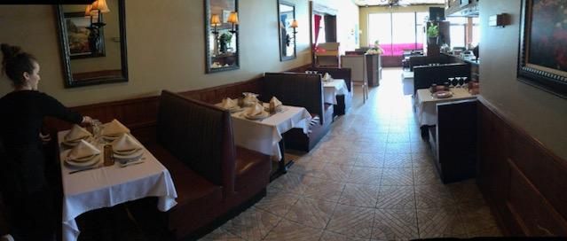 A woman is standing in a long hallway of a restaurant.