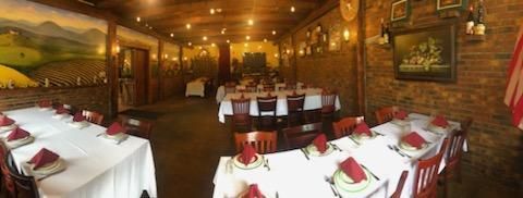 A long table in a restaurant with plates and napkins on it.