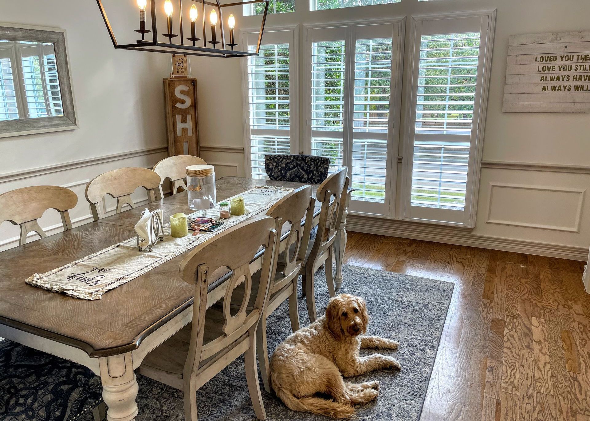 A dog is laying on the floor in a dining room next to a table.