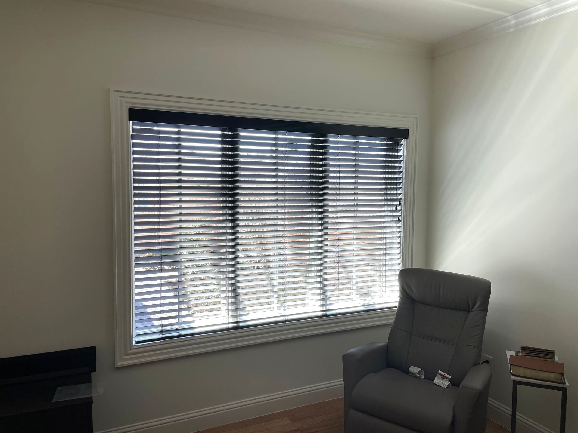 A living room with a chair and a large window with blinds.