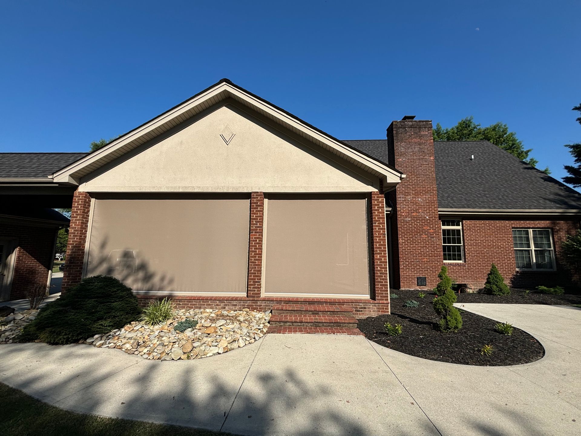 A brick house with a screened in porch and a driveway