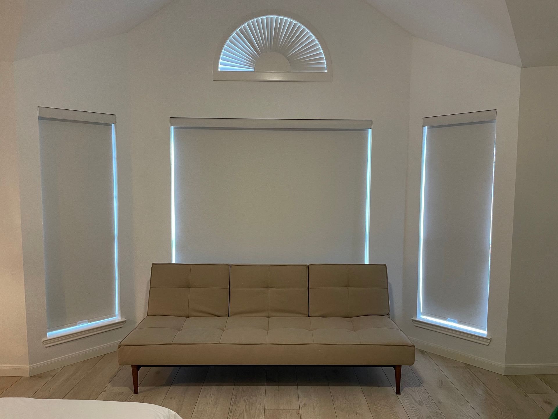 A living room with a couch and three windows