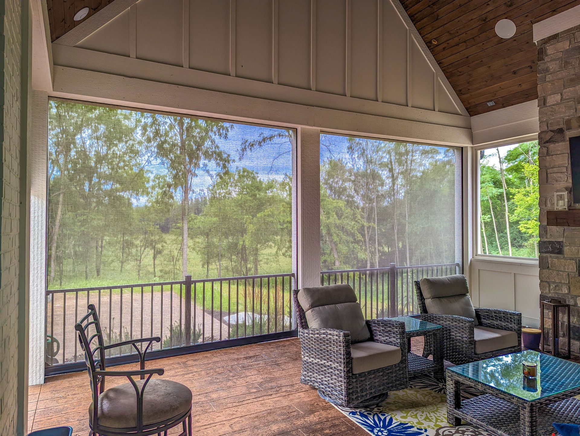 A screened in porch with wicker furniture and a fireplace.